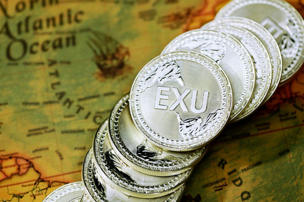  Foreign exchange Stack of silver EXU cryptocurrency coins placed on a world map background.